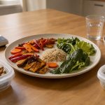 Repas équilibré composé de légumes rôtis, salade verte, céréales complètes et fruits rouges, présenté sur une table en bois avec des contenants réutilisables.